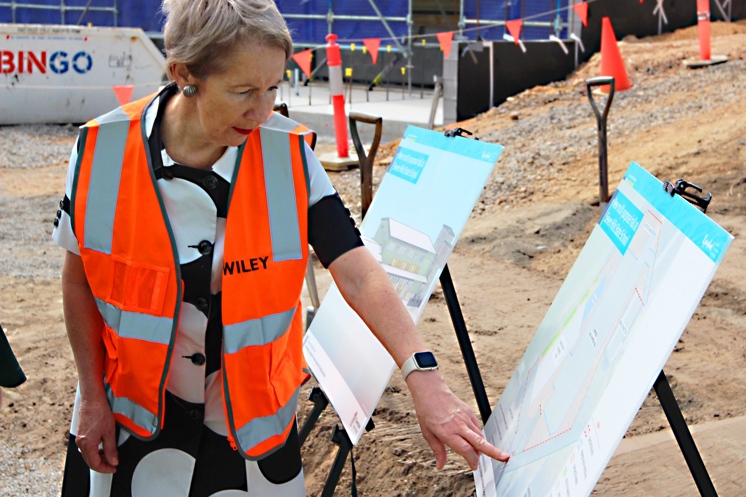 Hon. Di Farmer reviewing multi-purpsoe hall plans at the sod turning ceremony at Seven Hills State School